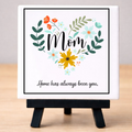 Decorative sign with floral design and text on a ceramic tile and resting on wood easel